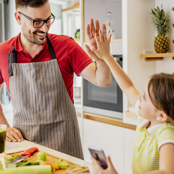 dad high-fiving kid while making a meal