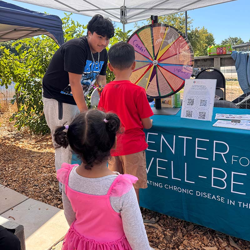 A boy helping a kid to spin a wheel.